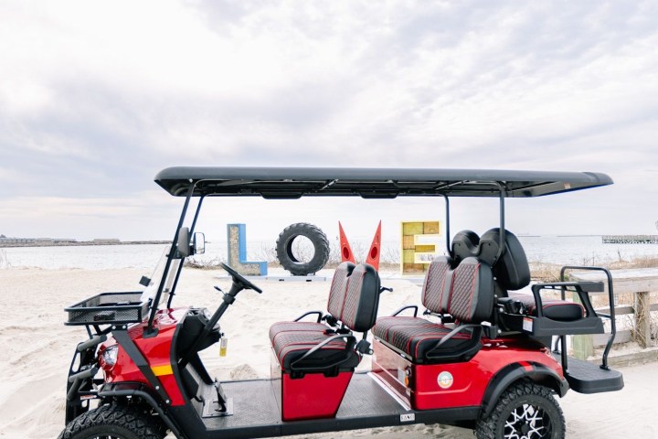 Red golf cart on a sandy beach with 'LOVE' letters in the background.