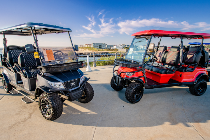 Two colorful golf carts parked on a seaside promenade.