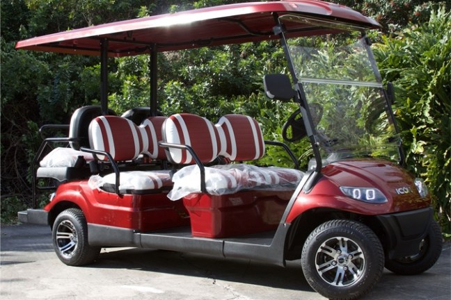 Red golf cart with a canopy and three rows of seats.