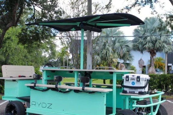 Turquoise pedal-powered bar on wheels with a canopy.